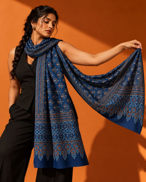 Woman in black holding out the indigo Nilufar block-print modal silk stole against an orange wall