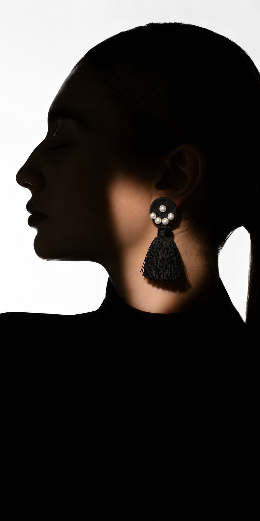 Earrings for jeans and a top: Black Bloom earrings worn on the ear, a cluster of white pearls on a black fabric disc above a black thread tassel, House of Falguni
