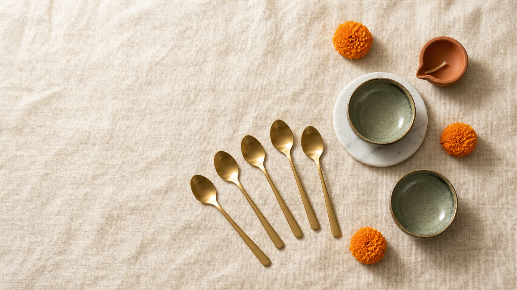 Handcrafted Diwali gifts from House of Falguni, with gold-tone dessert spoons and hand-glazed ceramic set out on a festive table