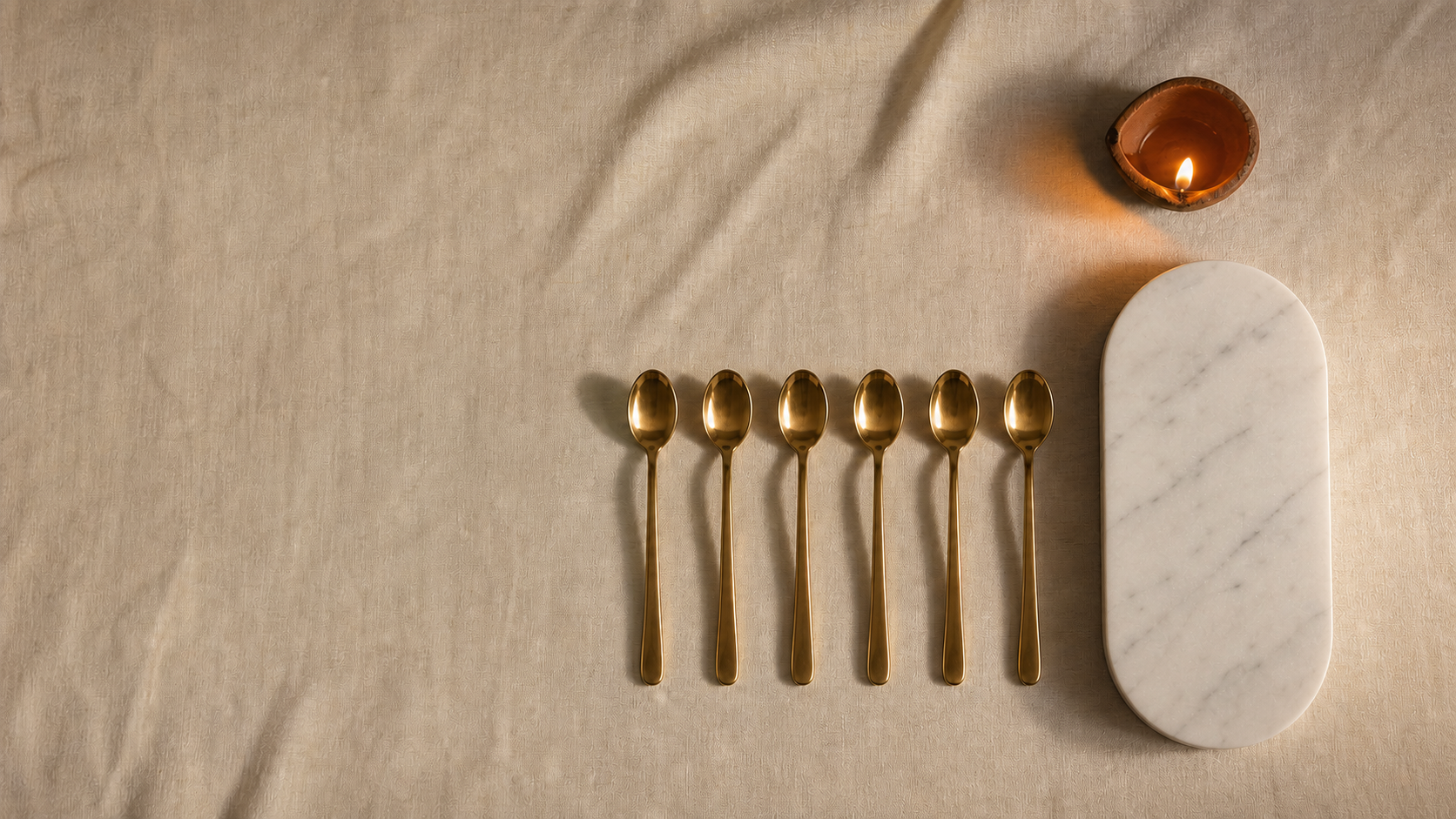 Gold-tone stainless steel dessert spoons and handcrafted tableware laid out for a Dhanteras 2026 utensil purchase