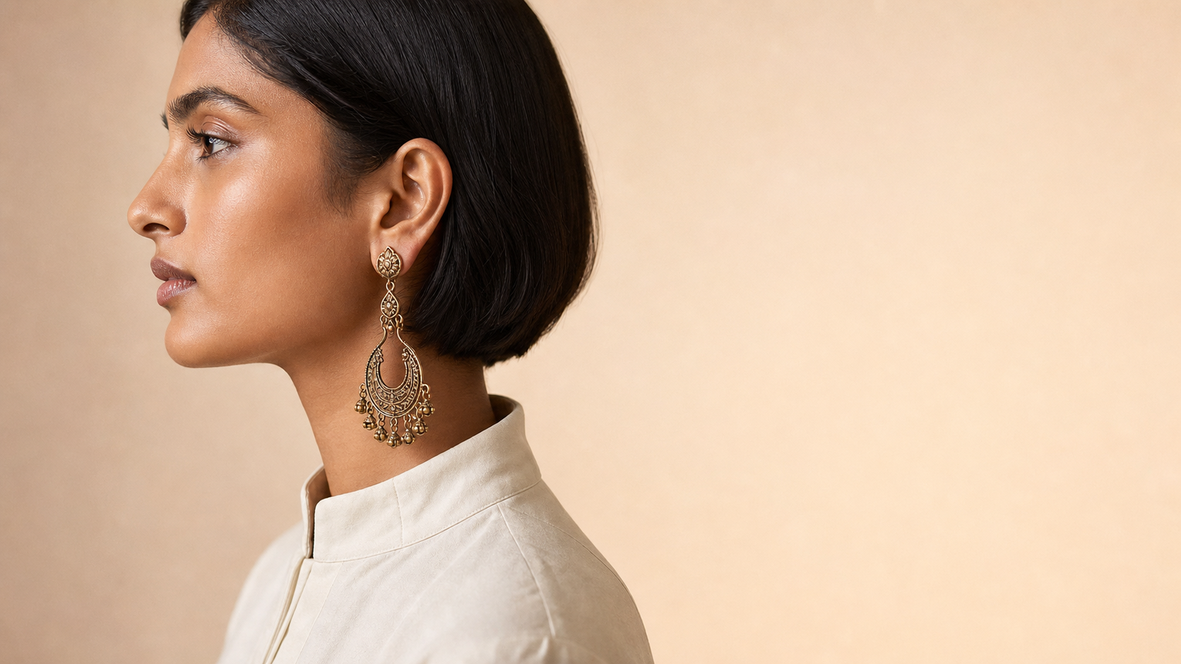 Woman with short hair and a high neckline wearing a long handcrafted chandbali drop earring — House of Falguni