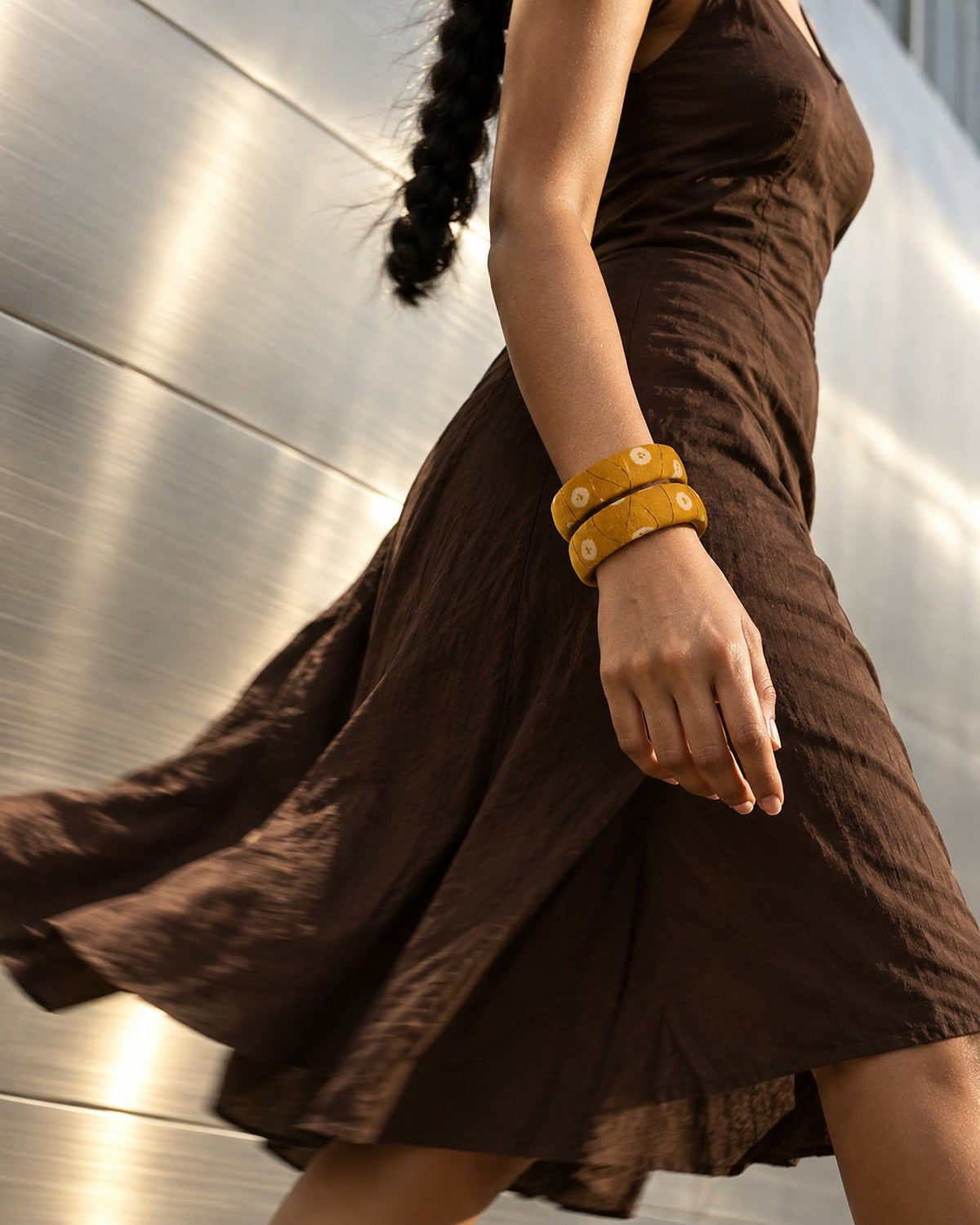 Mustard floral fabric bangles worn with a brown cotton dress while walking