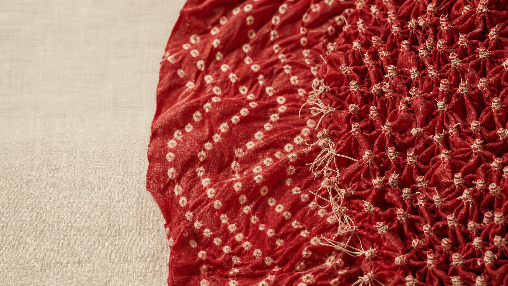 Red bandhani cloth with hand-tied knots partly opened to reveal the dot pattern — how to identify real bandhani, House of Falguni