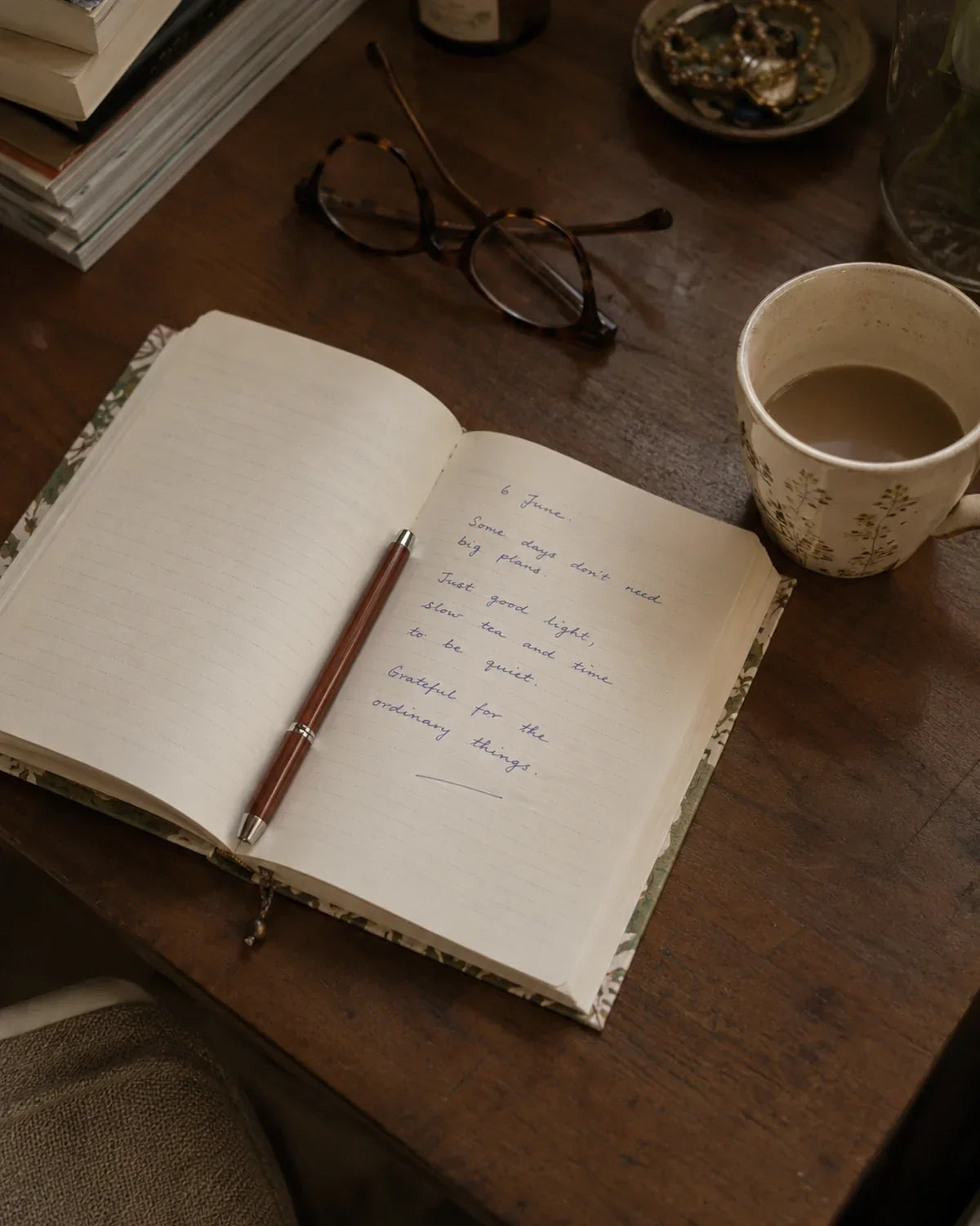 Lined fabric diary open on a wooden desk with a dated handwritten entry, reading glasses and a cup of chai, what to write in a diary, House of Falguni