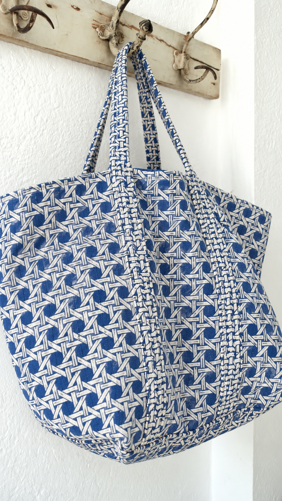 Samudra blue cane print tote hanging from a wall hook, showing its depth