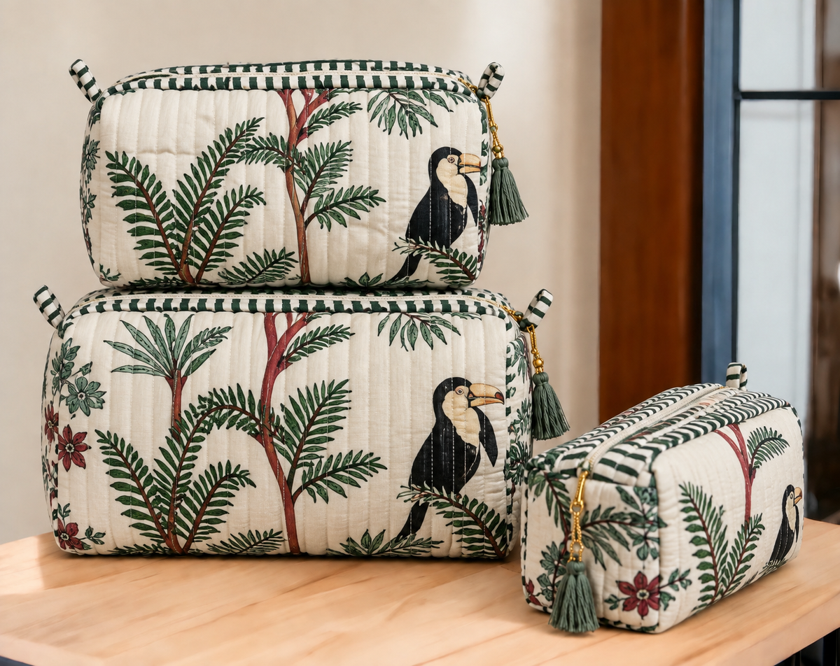 Angan pouch set stacked on a wooden table, showing the three sizes and tasselled zip pulls