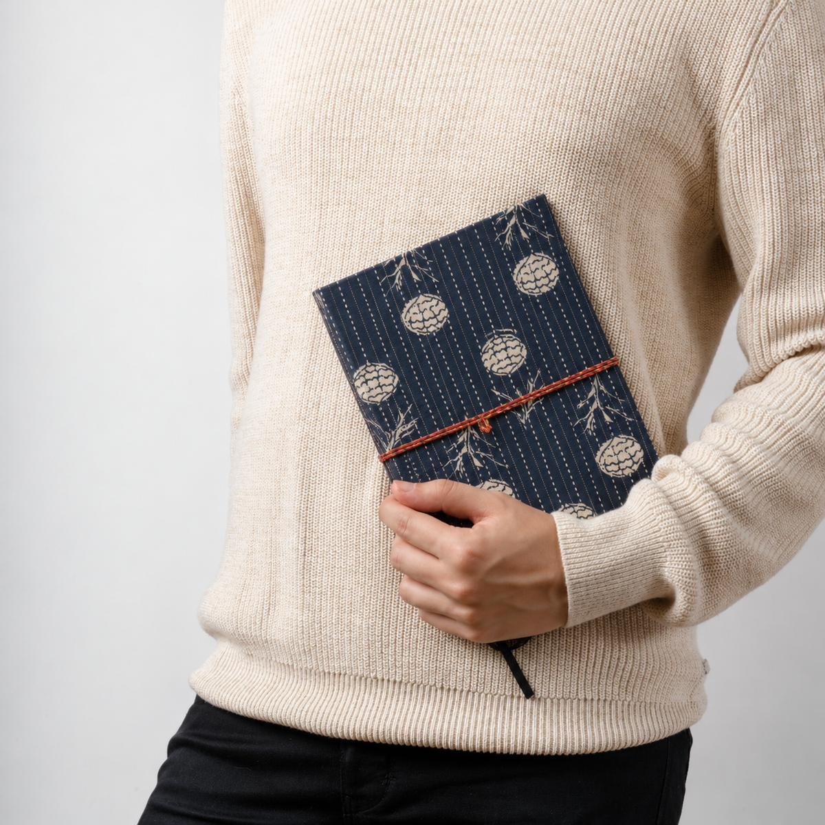 Navy Geometric block print fabric diary held at the waist against a cream knit sweater