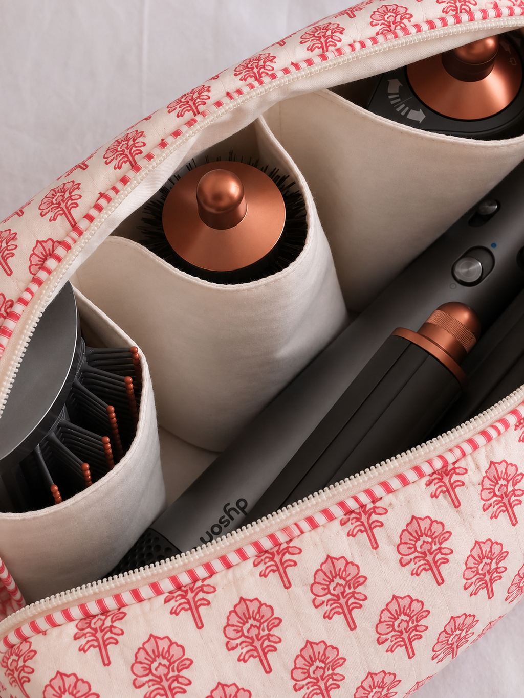 Gulaab red buti quilted hair tool bag, close-up inside with a Dyson Airwrap and its attachments in the inner pockets