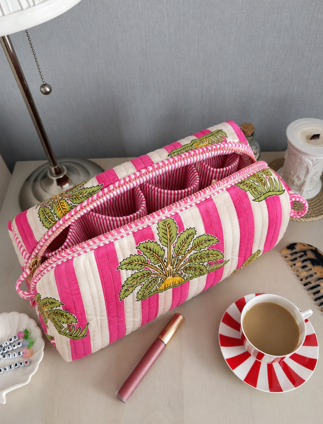 Gul quilted hair tool bag in pink and white stripes with green palm motifs, open to show the striped inner pockets