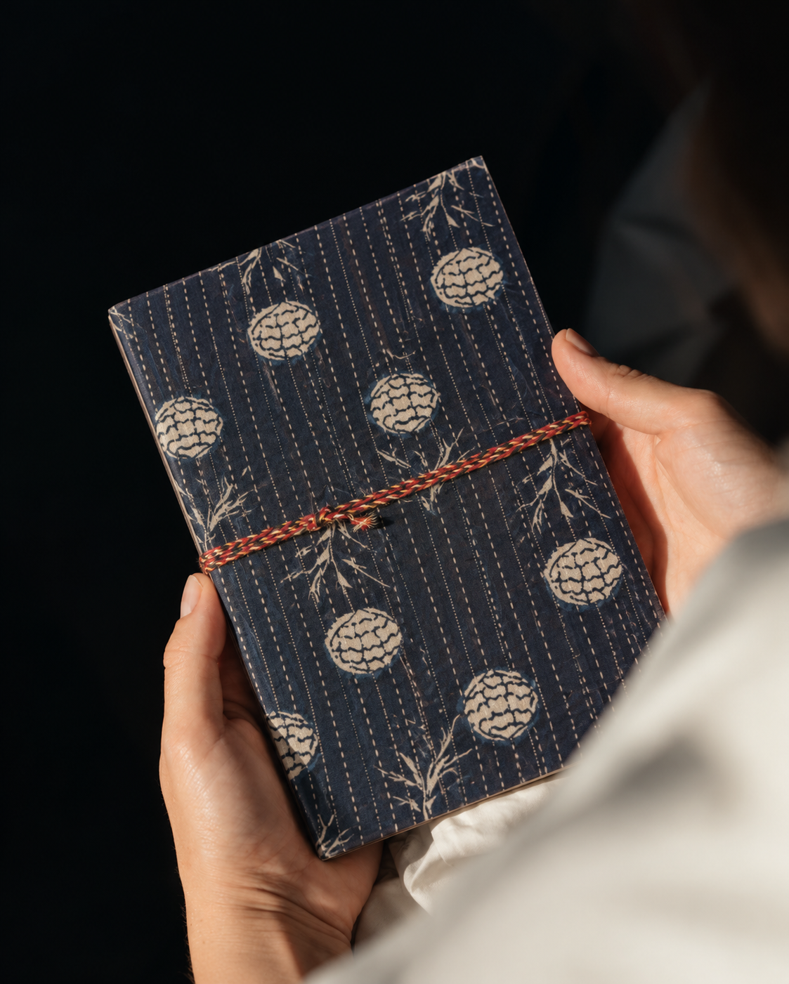 Navy Geometric block print fabric diary held in both hands against a black background