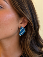Close-up of a Leher Sky Blue half moon earring on the ear: sky blue and white lehariya stripes with ghungroo bead points