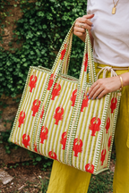 Aakar red lobster stripe quilted tote carried by hand outdoors, showing the green-and-white striped handles