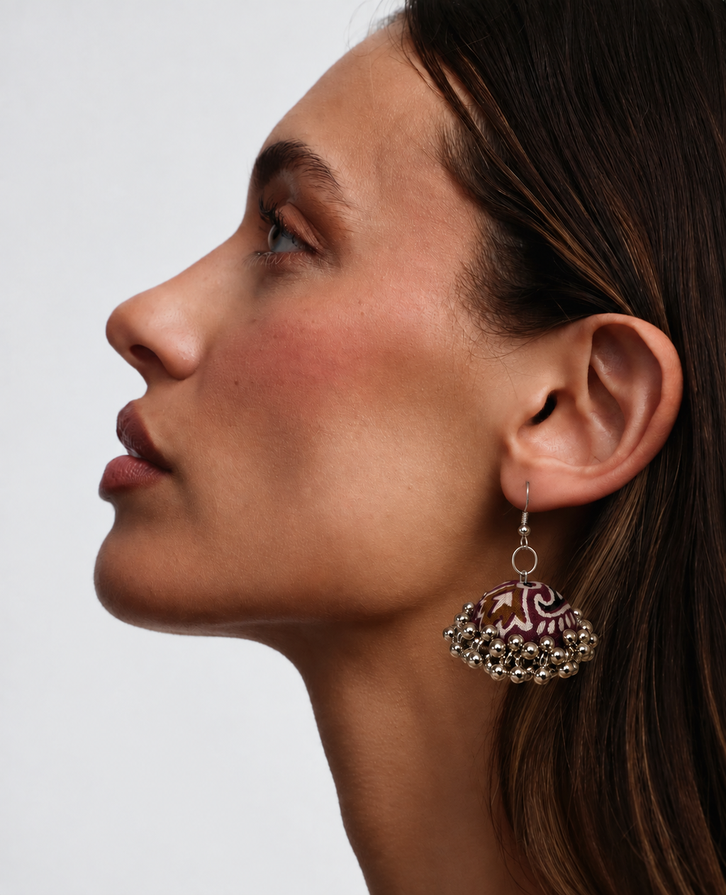 Side profile wearing the deep maroon and ivory floral jhumka