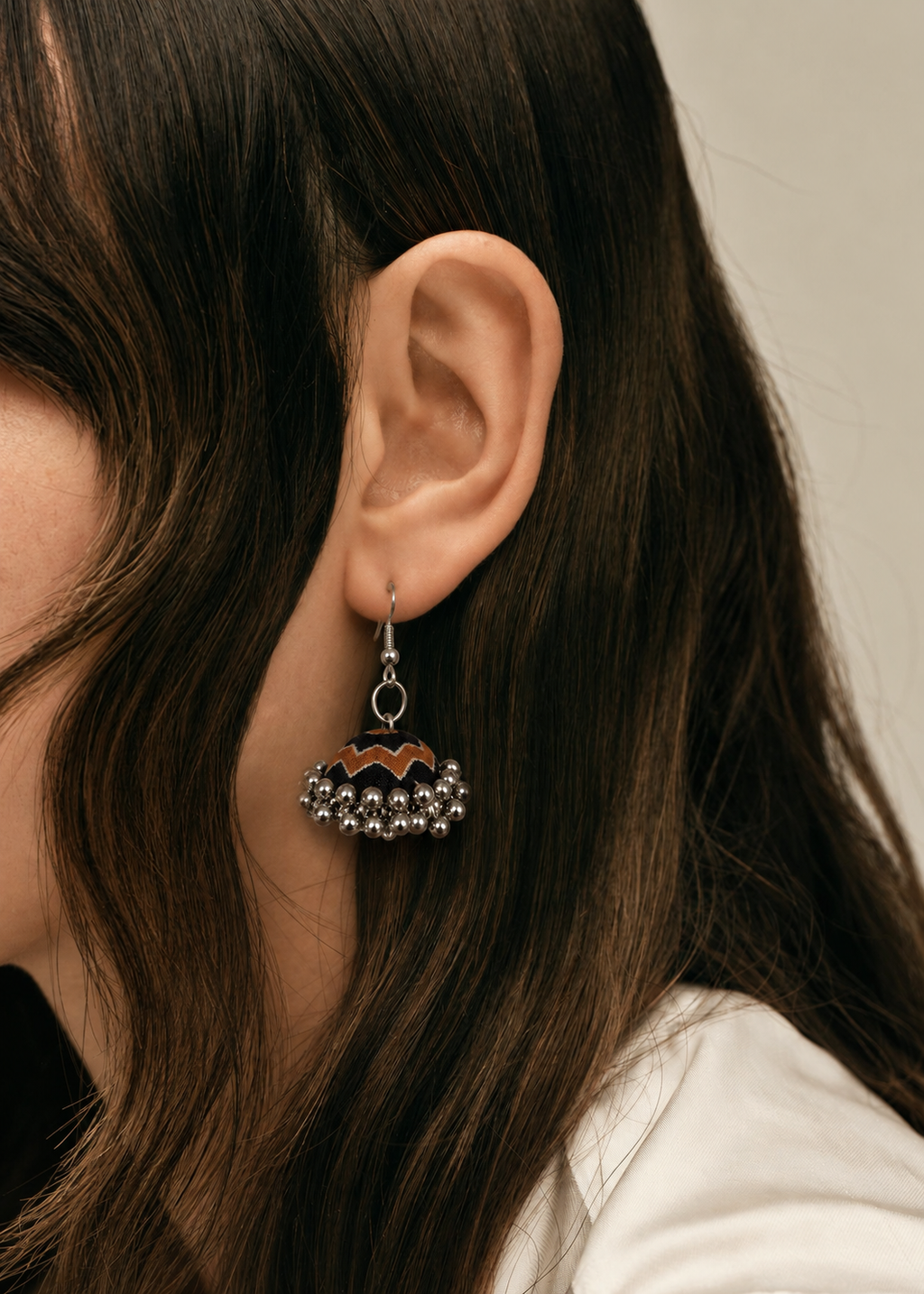 Near-black fabric jhumka earring with a rust-orange scalloped edge and silver bead fringe — House of Falguni
