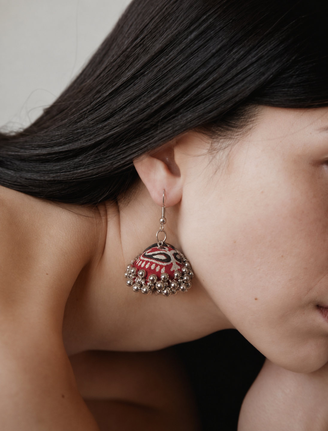 Profile view of the maroon zigzag jhumka against dark hair