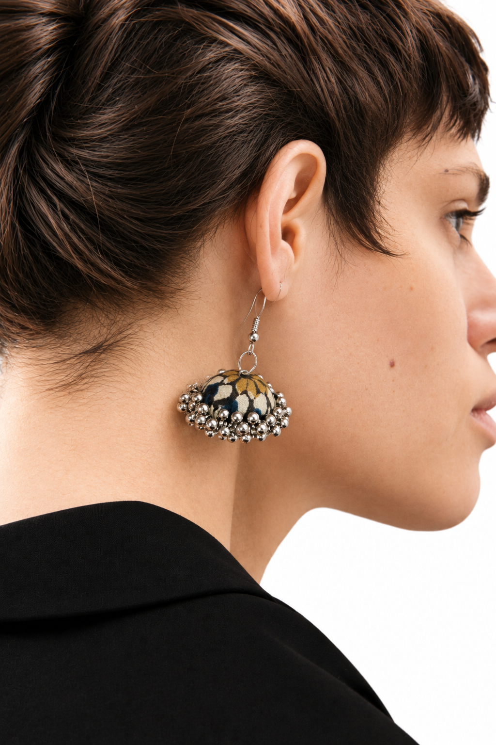 Profile view of a navy and ochre-gold fabric jhumka against a black blazer collar