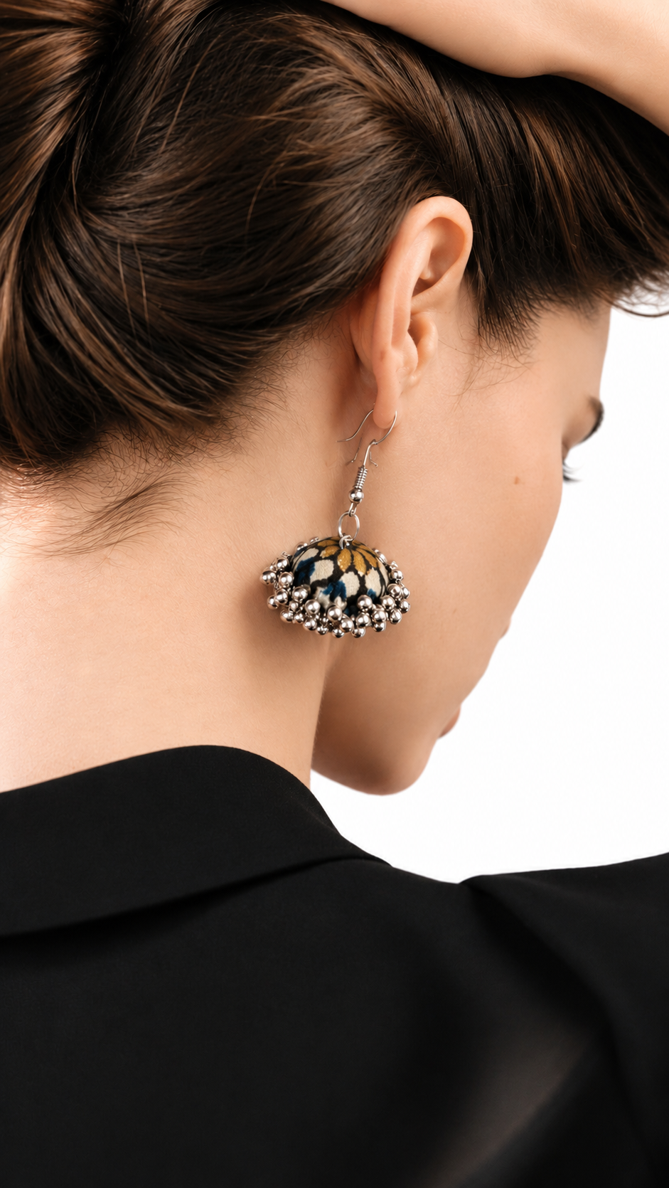 Mehfil Green jhumka worn with hair swept back and a black jacket, the navy dome catching the light