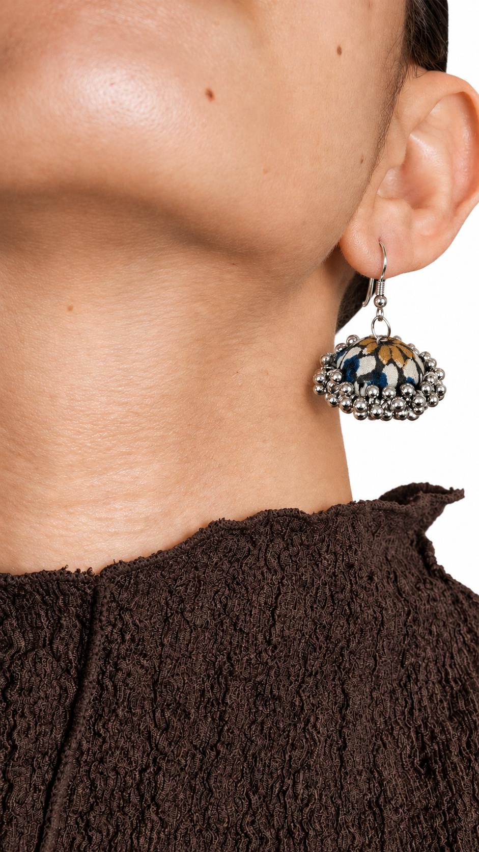Navy fabric jhumka earring with ochre-gold petal motifs and a silver bead fringe, worn with a brown textured top — House of Falguni