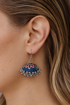 Close view of the Laalbagh jhumka, a red lotus opening against the navy dome