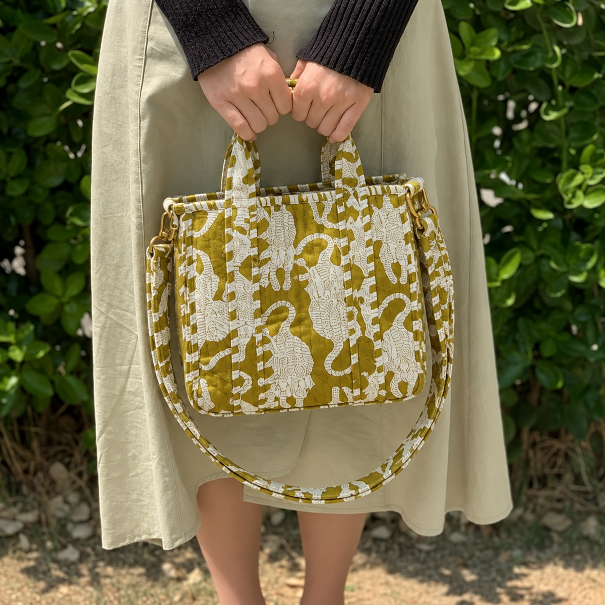 Matsya olive and white mini tote held in front with both hands, showing its size