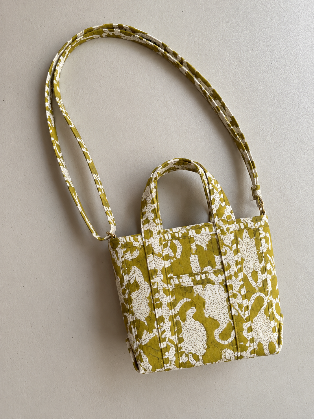 Matsya olive and white mini tote lying flat with its long matching strap
