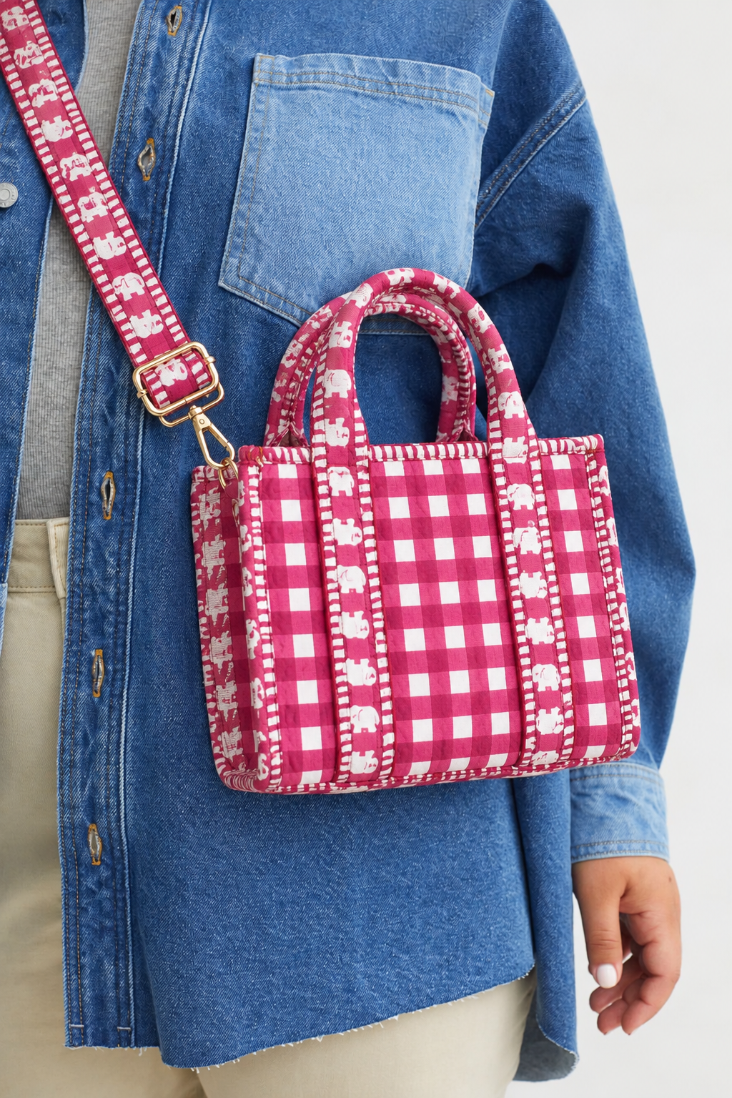 Rani pink gingham mini tote on a denim jacket, showing the gold-tone adjustable buckle and snap hook on the strap