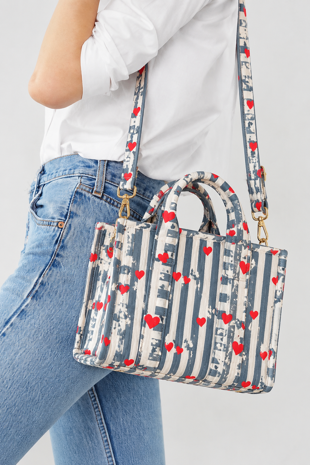 Jal grey stripe quilted mini tote worn crossbody on the long strap, with jeans and a white shirt