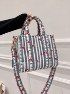 Jal quilted mini tote held by its two top handles, with the long strap hanging below