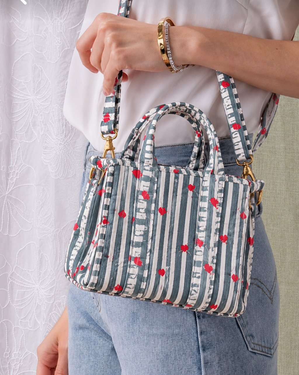 Jal grey and white striped mini tote carried by hand, showing its size against the body