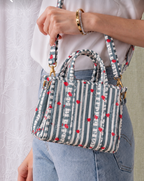 Jal grey and white striped mini tote carried by hand, showing its size against the body