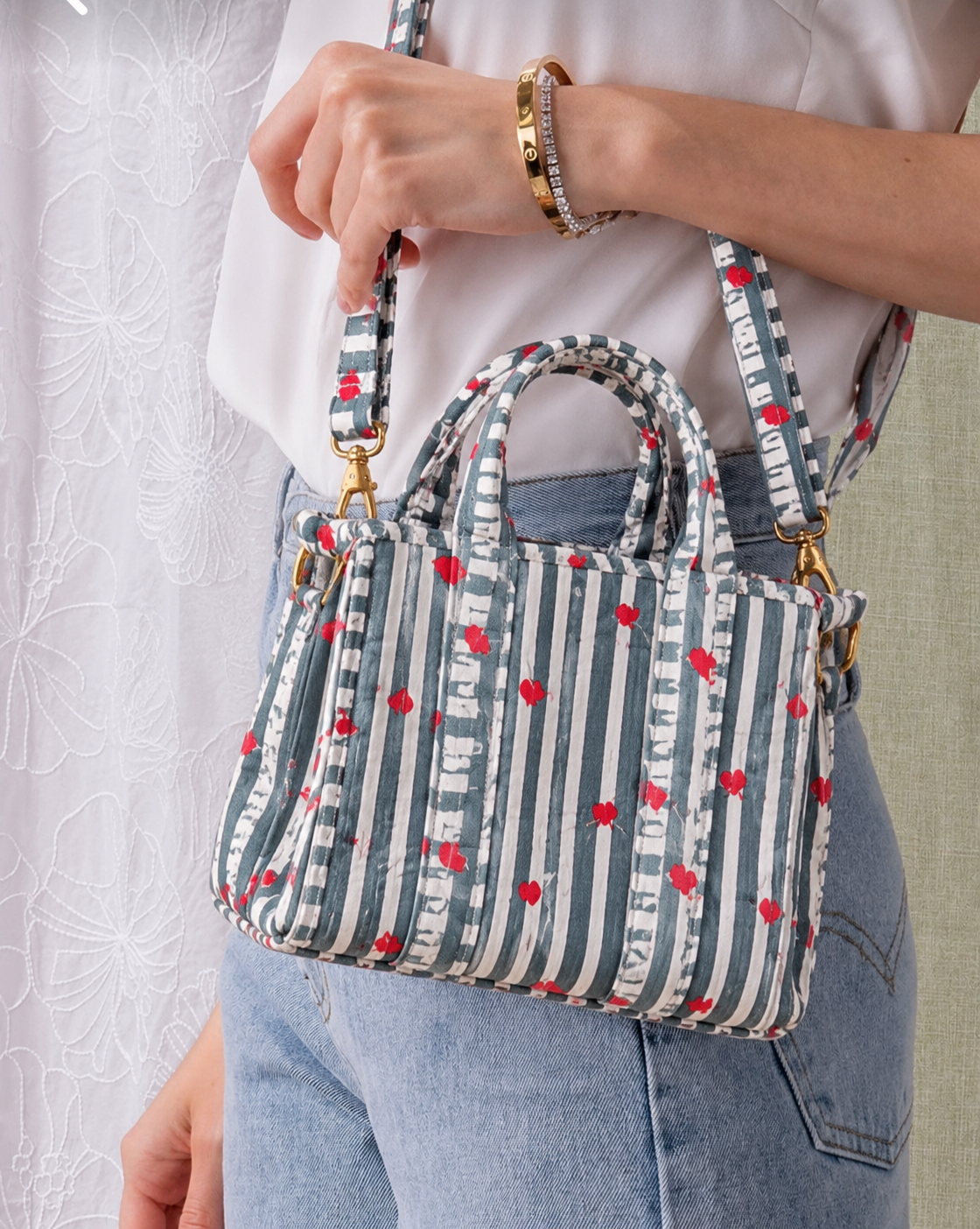 Jal grey and white striped mini tote carried by hand, showing its size against the body