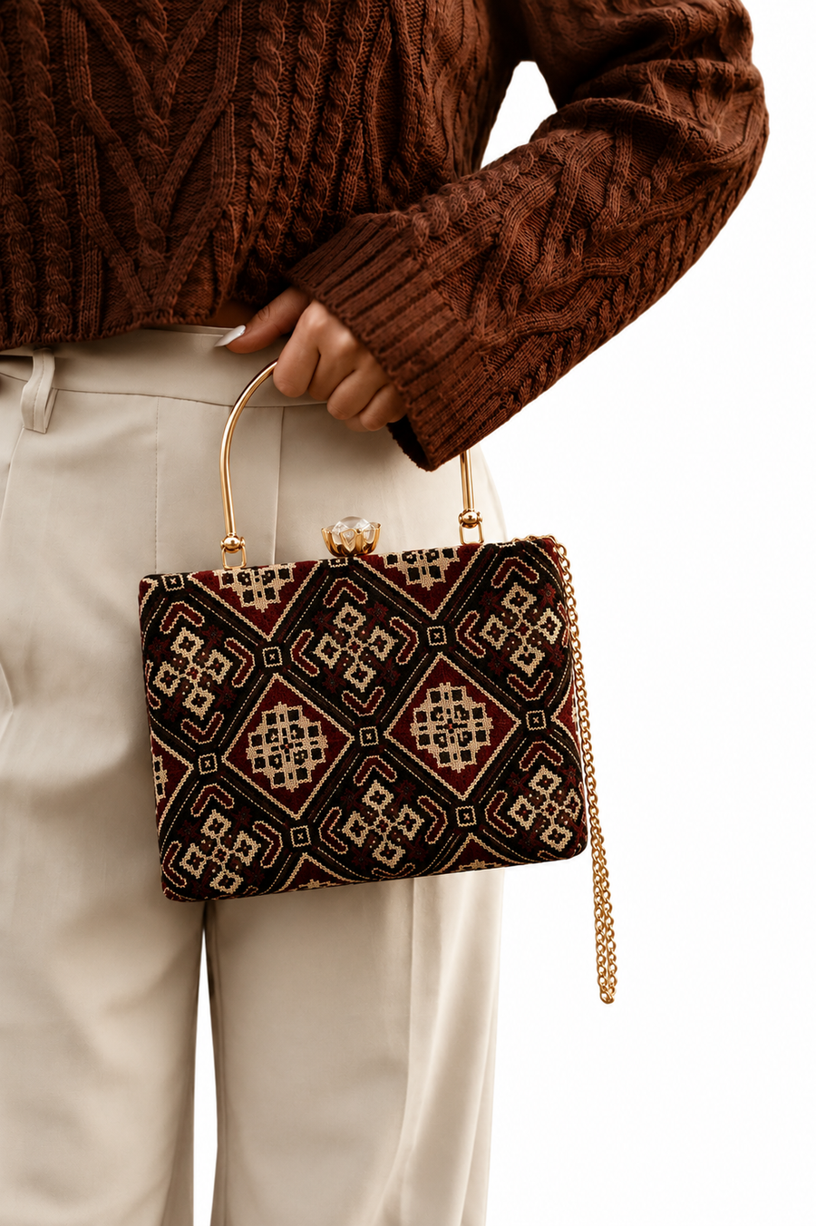 Ruhani maroon Ajrakh block-print Mashru silk handbag with diamond lattice pattern, held by hand against cream trousers, House of Falguni