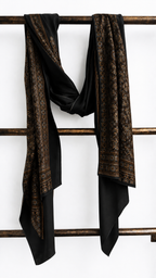 Shahi Ajrakh black modal silk stole hung on a wooden ladder, showing its hand block-printed border