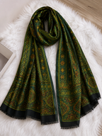 Nilufar Sheesh Mahal green Ajrakh modal silk stole laid on white fur, gold motifs and banded border
