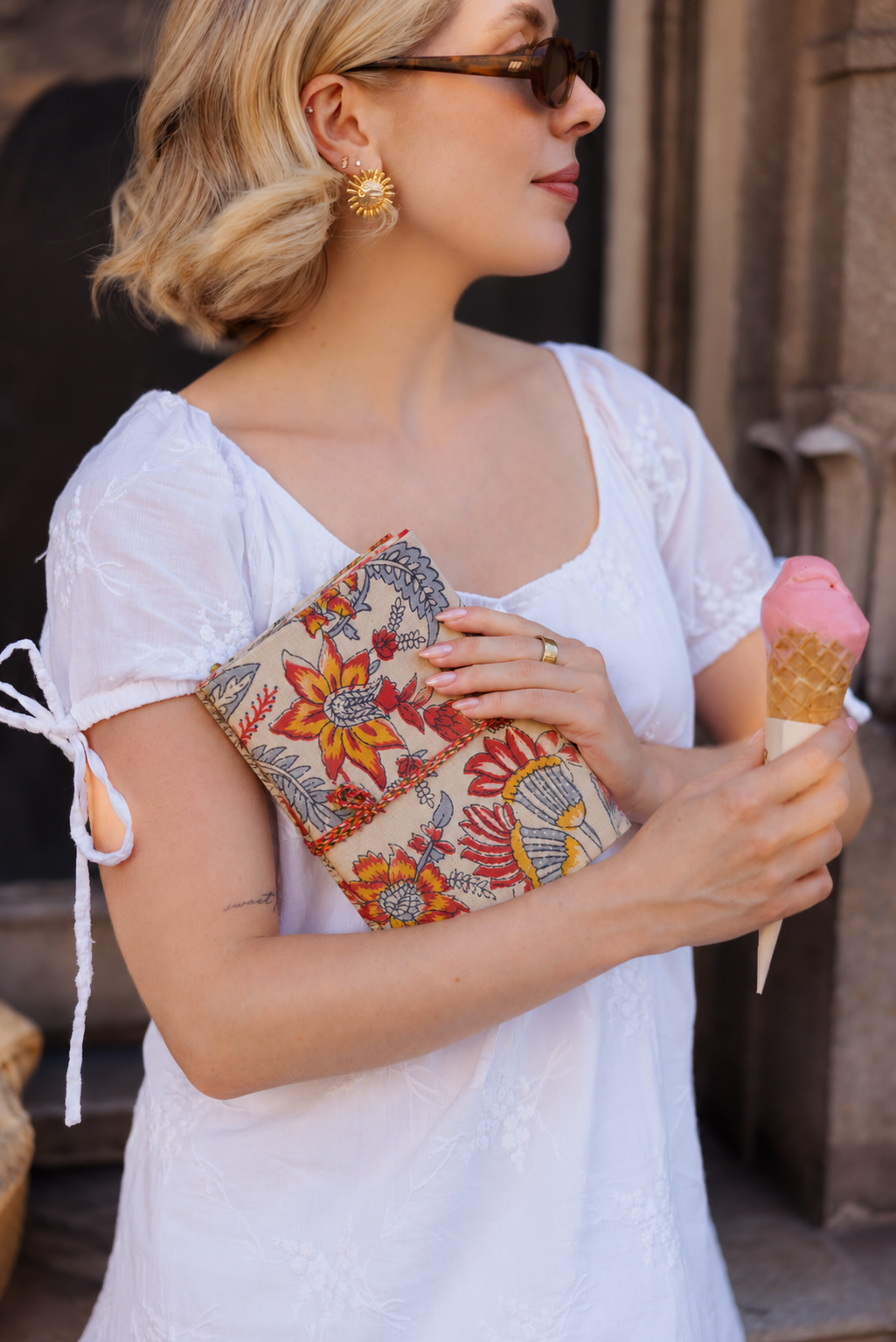 Hara Mahal block print fabric diary held against a white puff-sleeve dress, an ice cream cone in the other hand