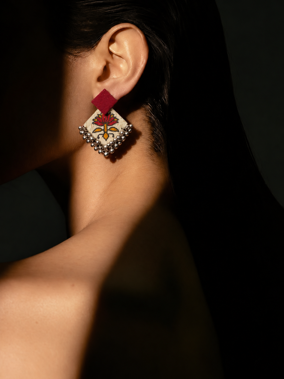 Fuchsia Floral Geometric Ghungroo Earrings in soft shadow: fuchsia square stud over a cream fabric diamond printed with a pink and orange flower