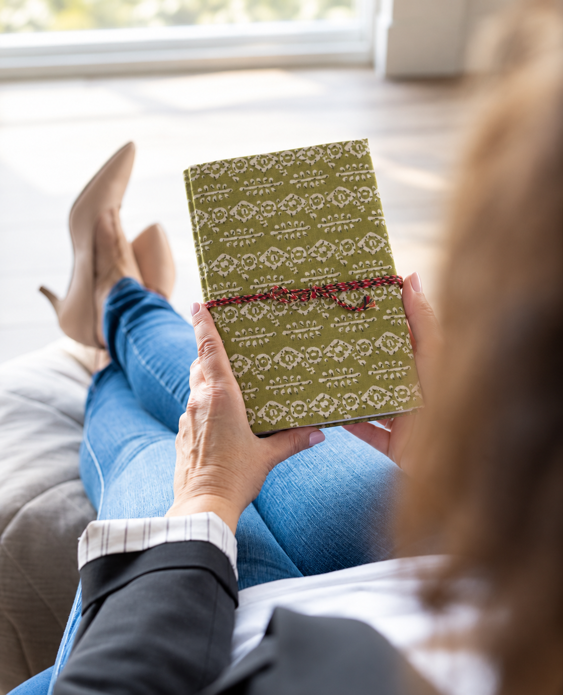 Mehendi Buti block print fabric diary read over the shoulder by someone lounging in jeans beside a bright window
