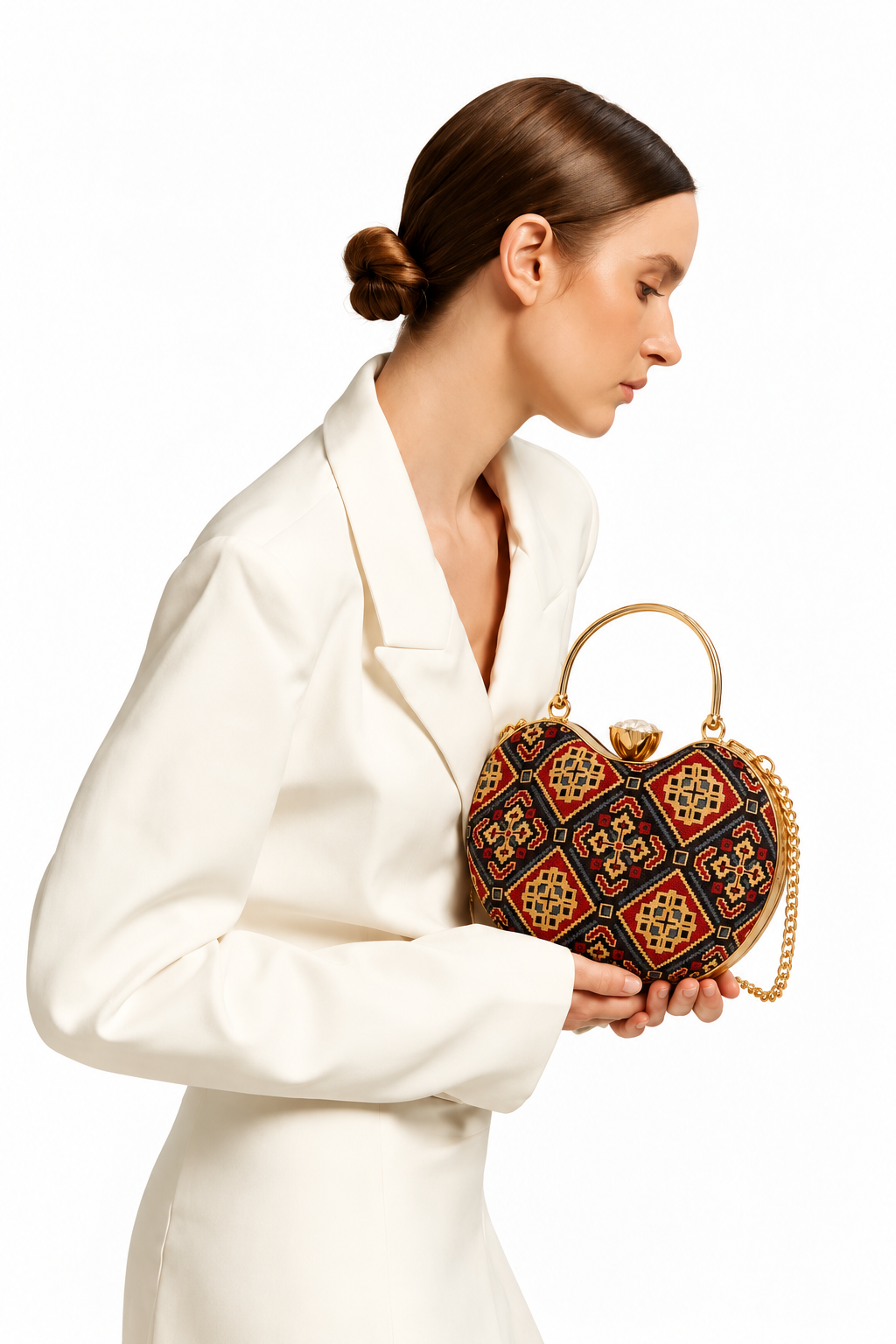 Kaali Adaa black Ajrakh Mashru silk handbag with red and mustard diamonds, held in both hands with an ivory blazer