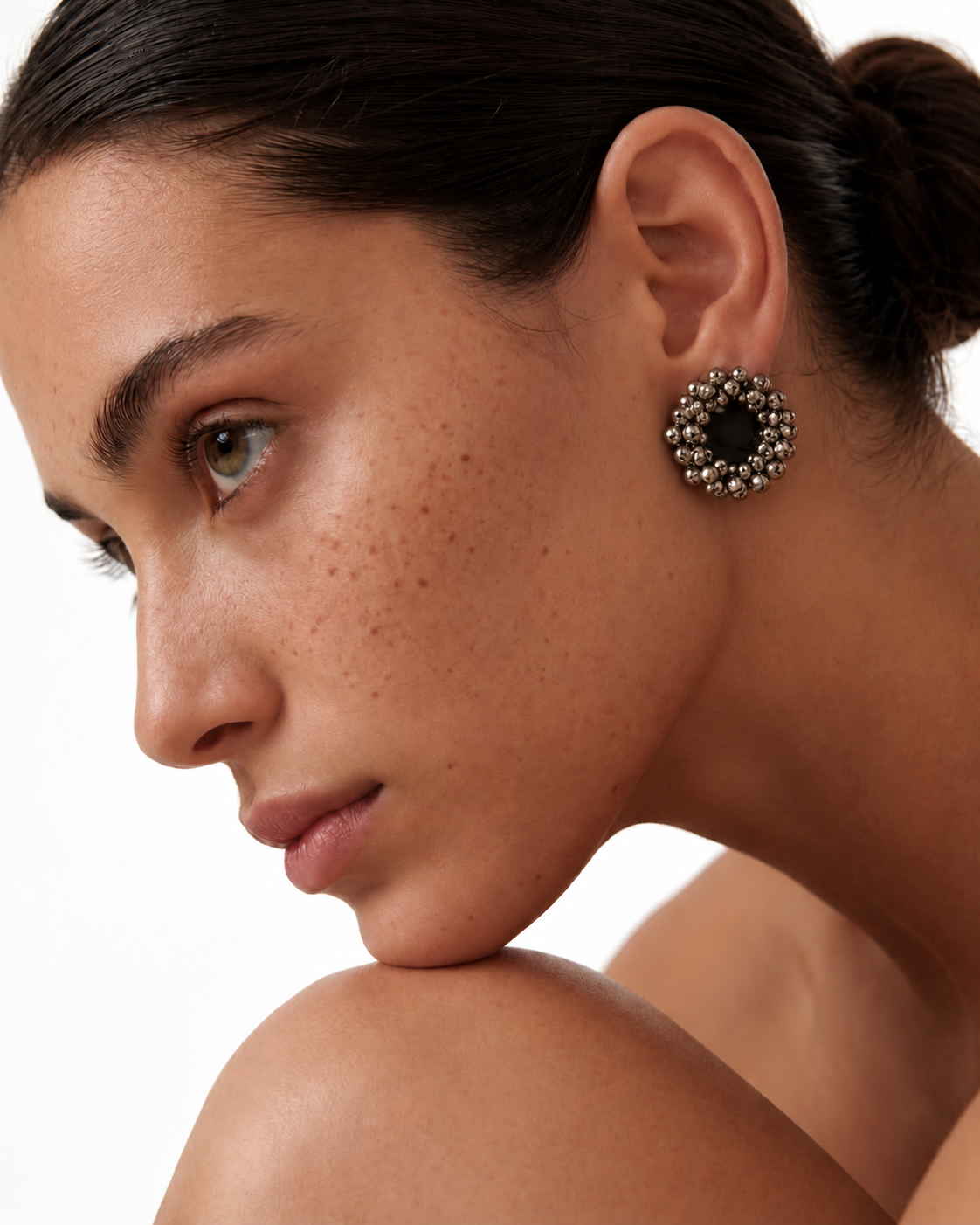 Charcoal Ghungroo Stud Earrings in profile with the hair in a bun: a round 1.5-inch stud, charcoal cotton centre and ghungroo bells