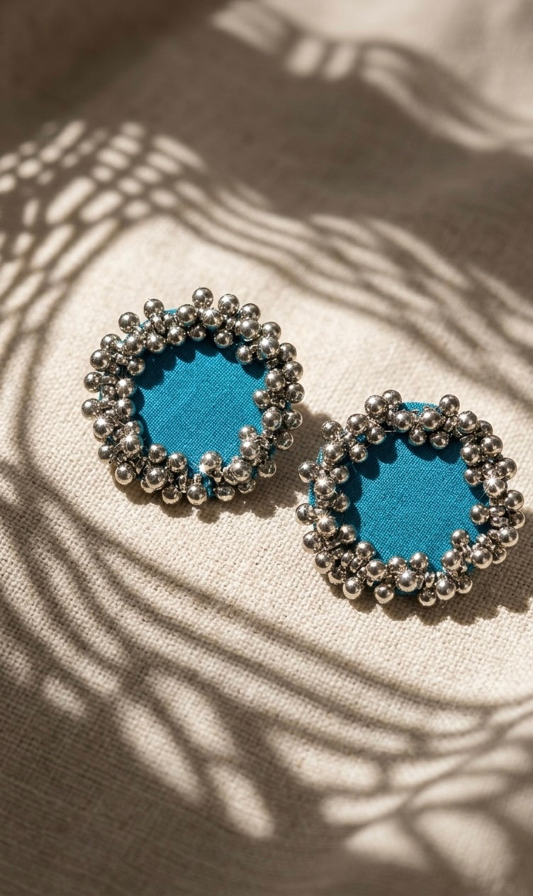 Sky Blue Ghungroo Stud Earrings, the pair photographed flat on linen: sky blue cotton centres ringed with two rows of ghungroo bells