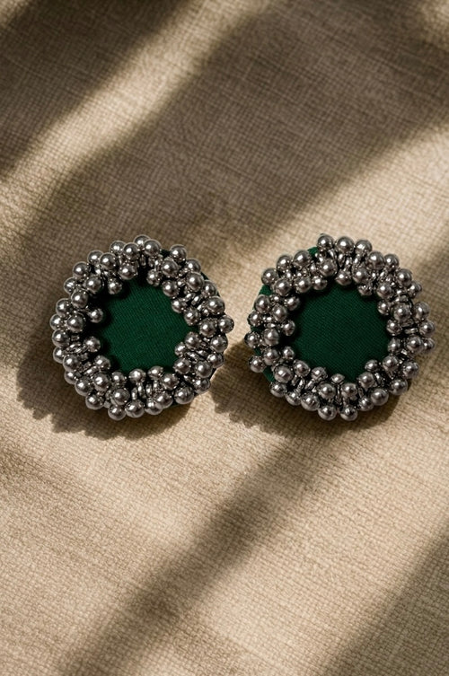 Green Ghungroo Stud Earrings, the pair photographed flat on linen: green cotton centres ringed with ghungroo bells
