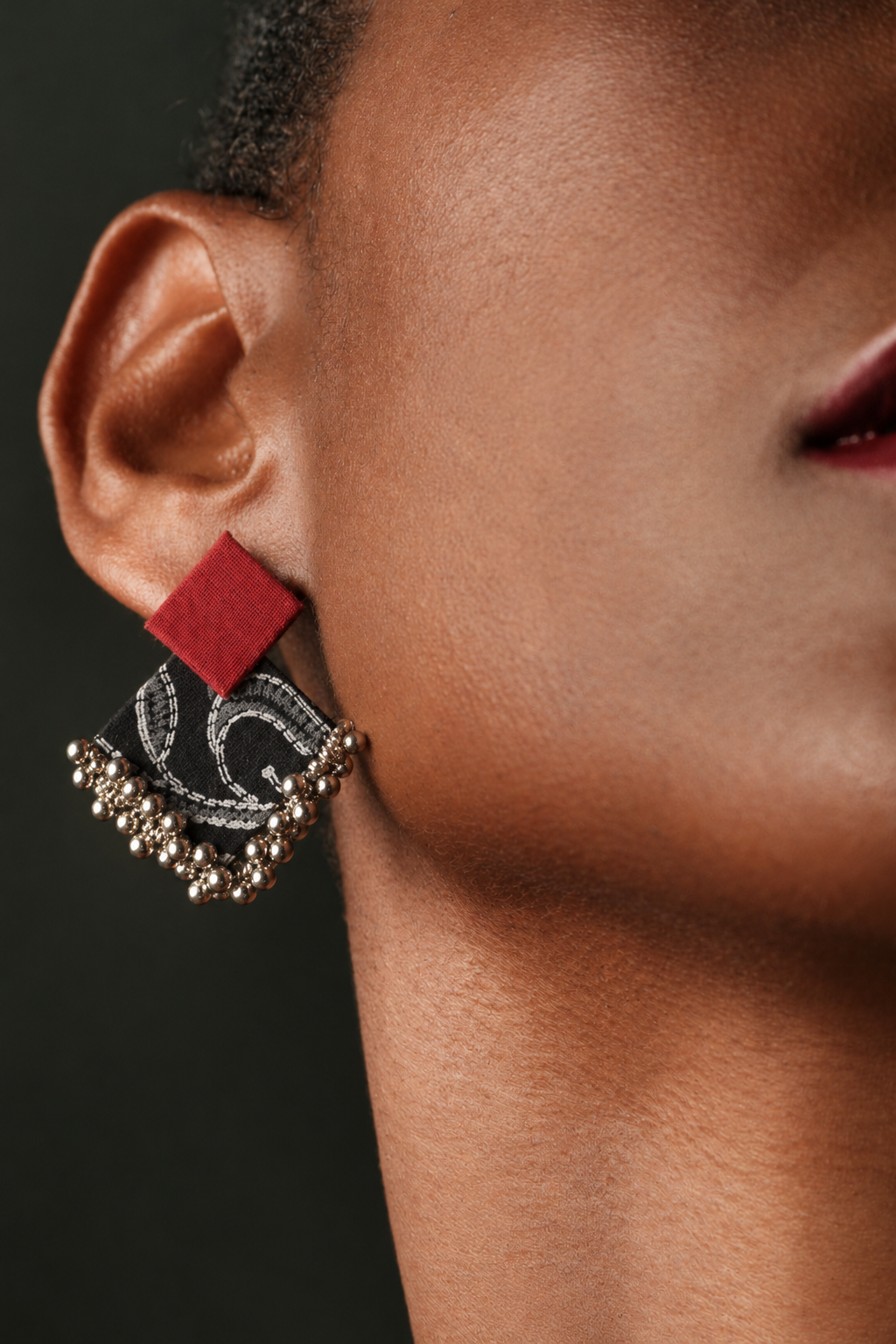 Close-up of a Black and Maroon Geometric Ghungroo Earring: deep red square stud over a black and white paisley-print fabric diamond with a row of ghungroo bells