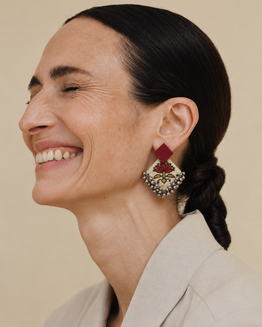 Fuchsia Floral Geometric Ghungroo Earrings worn with a beige blazer: fuchsia square stud over a cream floral-print diamond with ghungroo bells