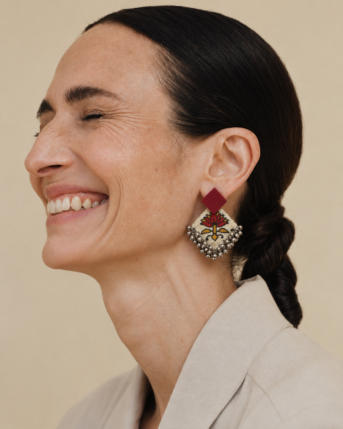 Fuchsia Floral Geometric Ghungroo Earrings worn with a beige blazer: fuchsia square stud over a cream floral-print diamond with ghungroo bells