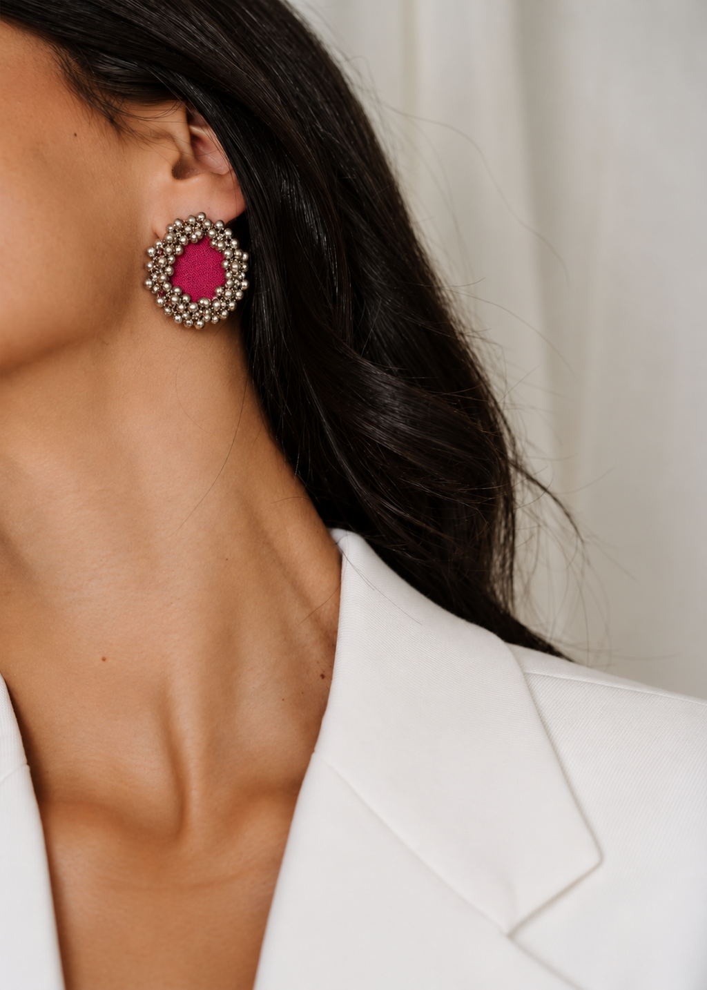 Fuchsia Pink Ghungroo Stud Earrings worn with a white blazer: fuchsia cotton centre ringed with two rows of silver-tone ghungroo bells