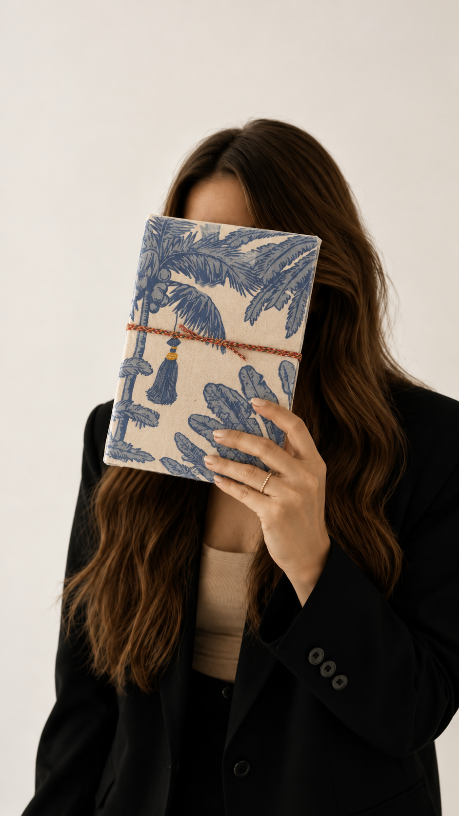 Neel Palash block print fabric diary held up to hide the face, worn with a black blazer