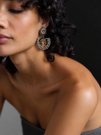 Black Chandbali Earrings with Ghungroo worn by a model with curly hair: black fabric crescent printed with mustard flowers, kundan top and ghungroo bells