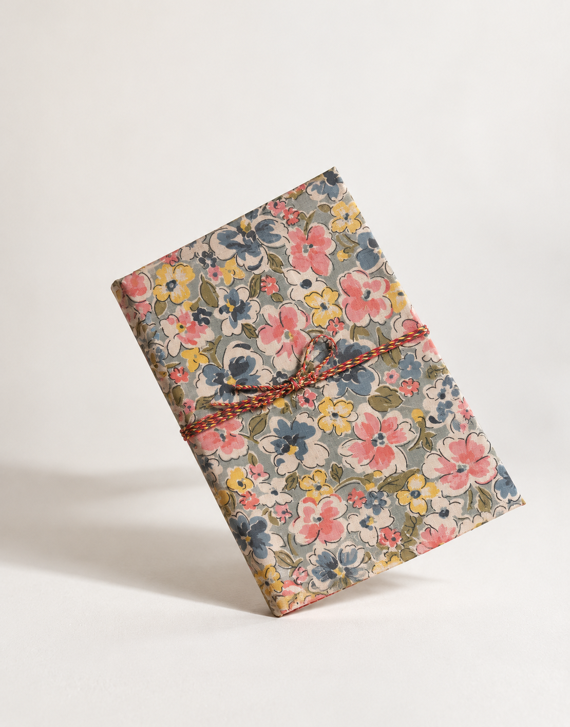 Bahar Medley block print fabric diary standing on its corner against a white backdrop, braided cord tied in a bow