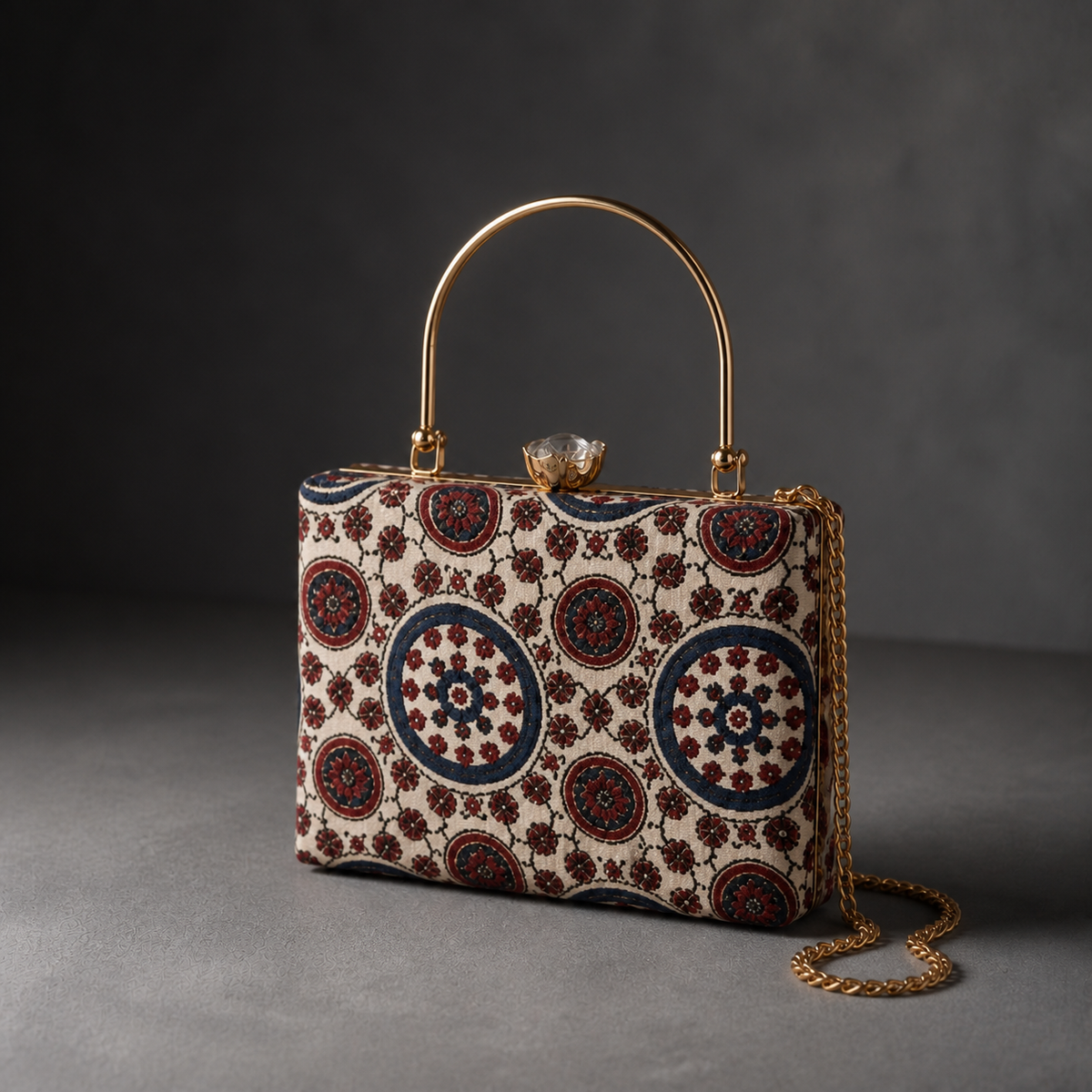 Aaina ivory and blue circular-print Mashru silk handbag in charcoal studio, with gold-tone top handle and detachable chain
