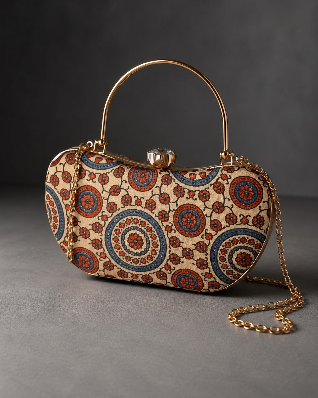 Aaina curved Mashru silk handbag, ivory ground printed with maroon and indigo concentric medallions, gold-tone frame, top handle and chain